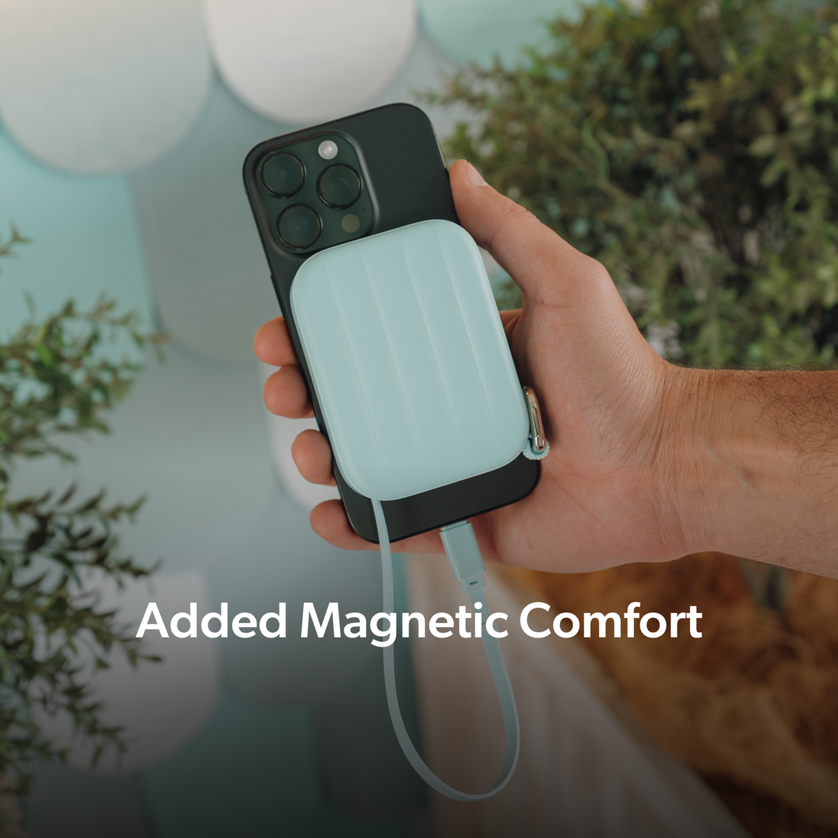 Sky Blue PowerPack Mini 2 magnetically held against a phone while charging through its USB-C cable.