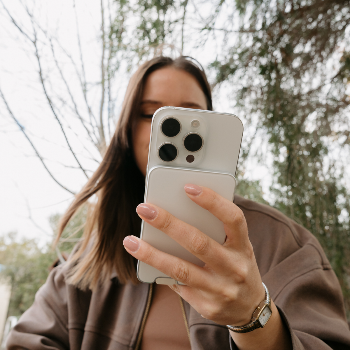 Woman using a smartphone with PowerPack Slim 3 attached outdoors