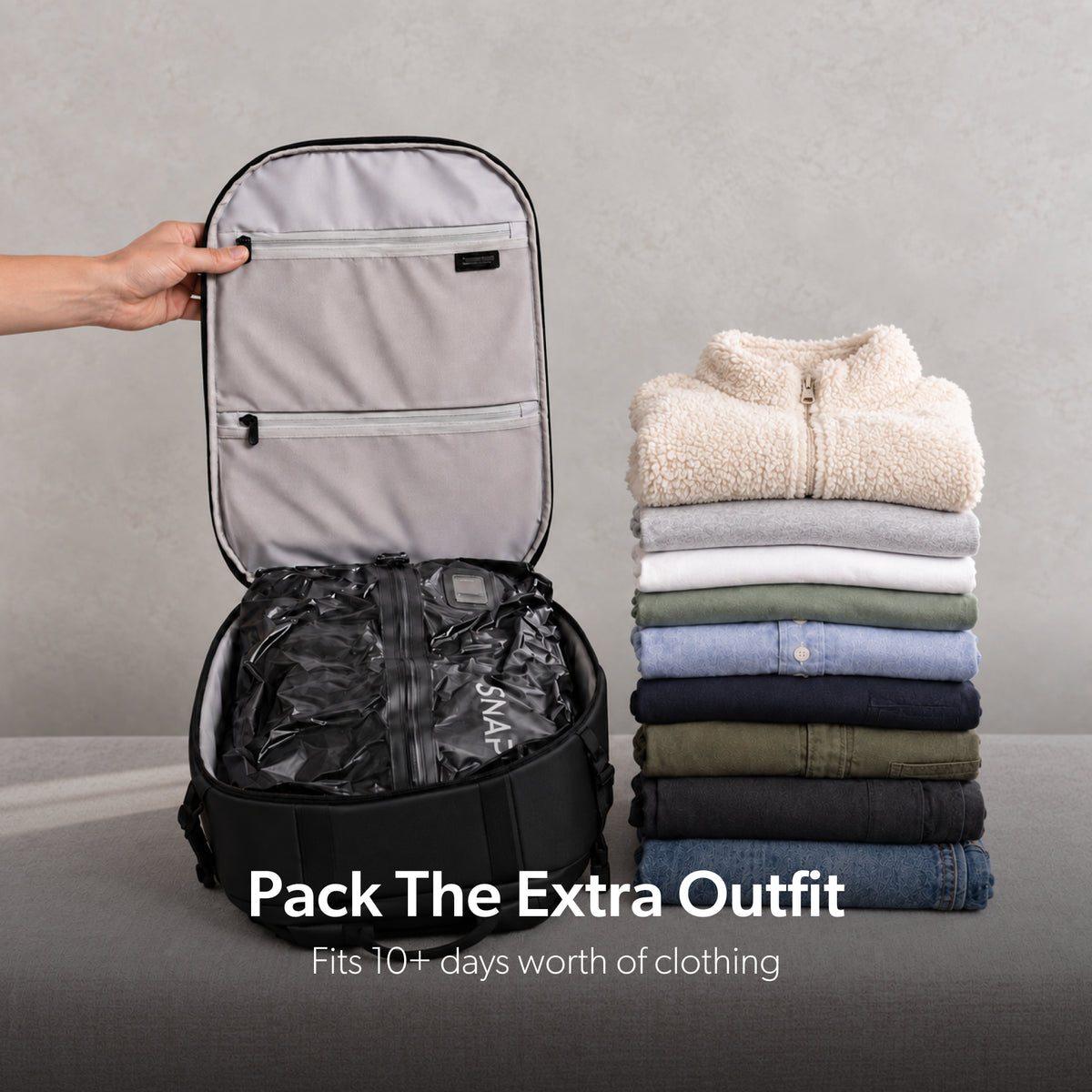 TRVLR Vacuum Bag in a backpack beside folded travel clothes
